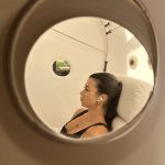 View through the porthole of a hyperbaric oxygen chamber showing a client during an HBOT for brain fog session at SILA Miami, FL.