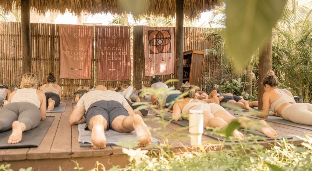 Yoga class resting in Child's Pose during a Soul Flow Yoga session at SILA Miami's jungle-style outdoor studio in Upper Buena Vista, FL
